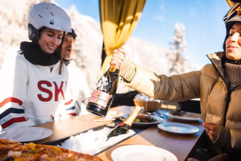 Anstoßen mit Champagner im Ski-Outfit vor Alpenkulisse in der Moet Champagner Gondel.